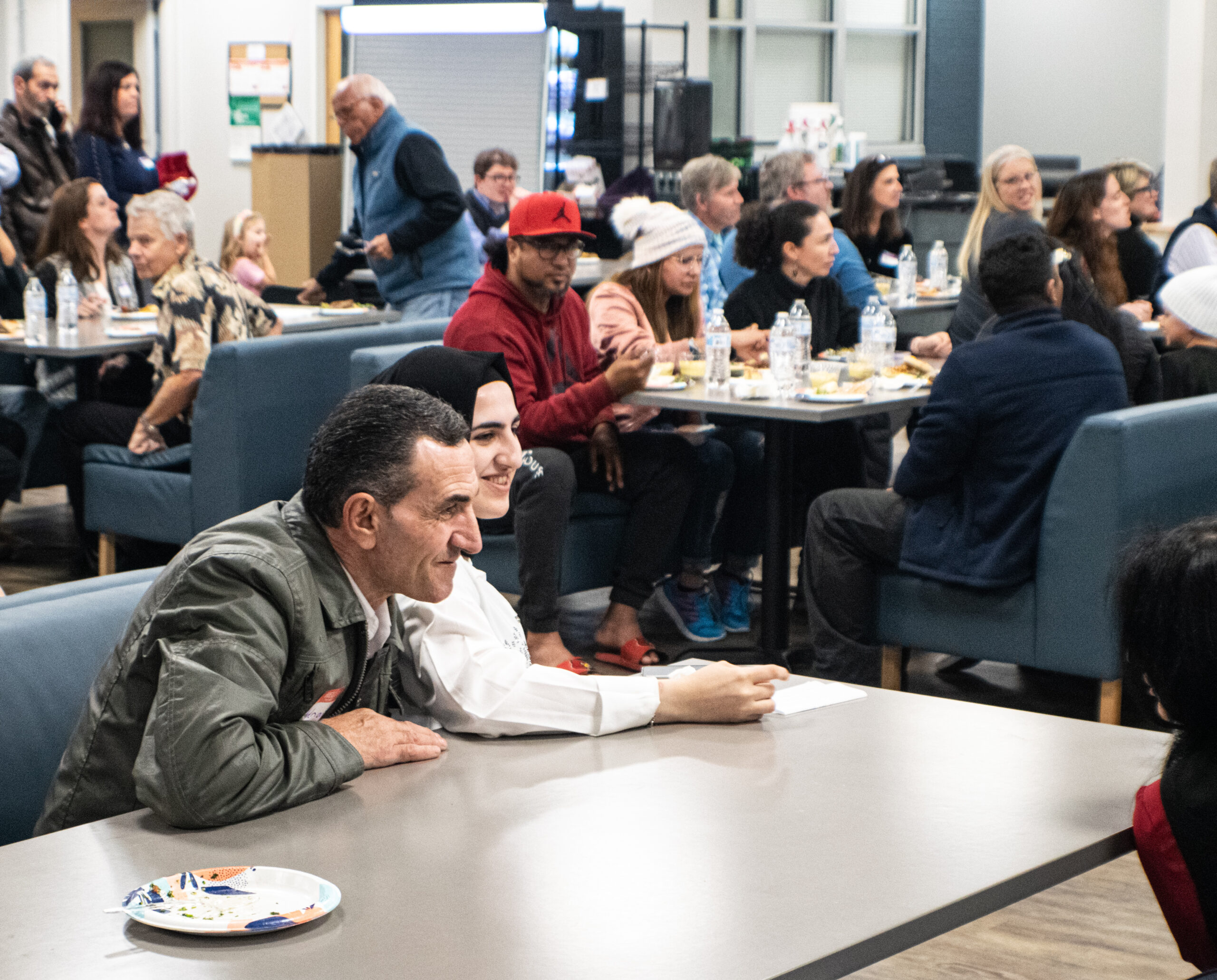 Father and Daughter adult learners sit at a table during a community dinner celebrating Syrian culture.